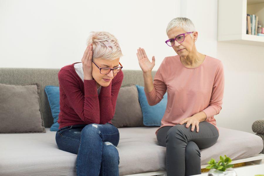 Image of mother and daughter sitting on couch engaged in disagreement